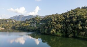 Peaceful lakeshore of Begnas Lake with reflections of hills and sky in Nepal